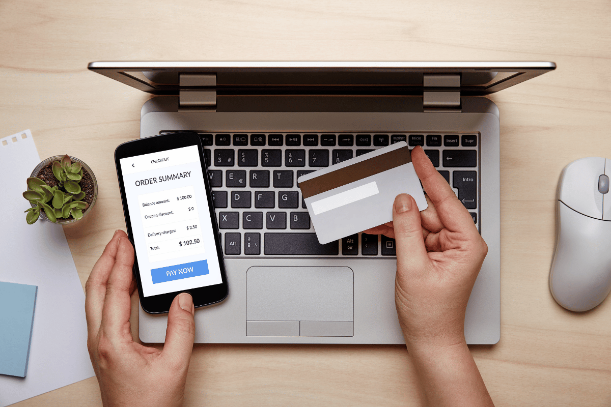 A woman using her credit card and phone to make an online e-commerce purchase.